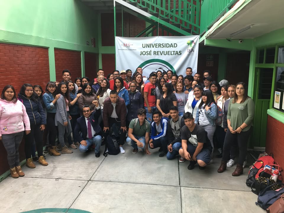 Integrantes de la comunidad reunidos frente a una manta de la Universidad José Revueltas.
